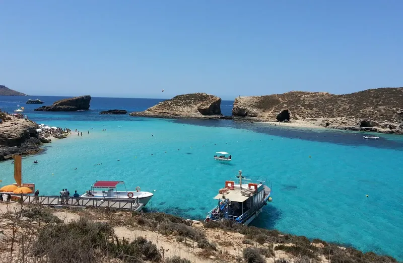 Vue d'une crique turquoise avec des bateaux et des baigneurs