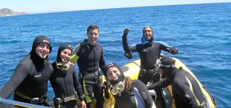 Groupe de plongeurs souriants sur un bateau pneumatique jaune en mer
