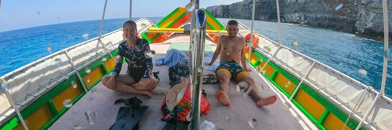 Deux plongeurs souriants se reposent sur le pont d'un bateau coloré