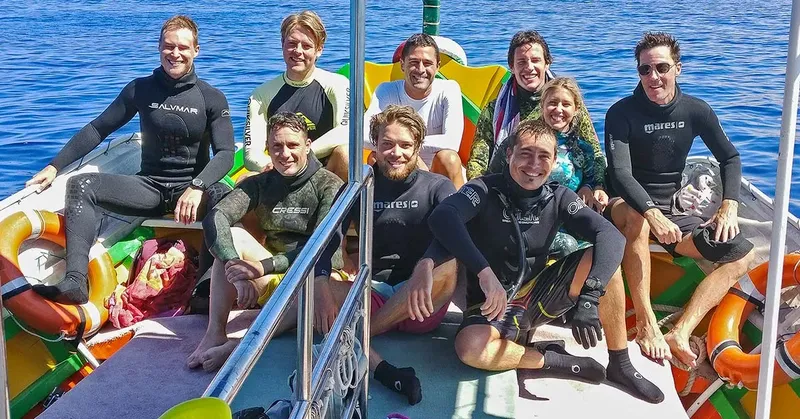 Groupe de plongeurs souriants à bord d'un bateau pneumatique coloré