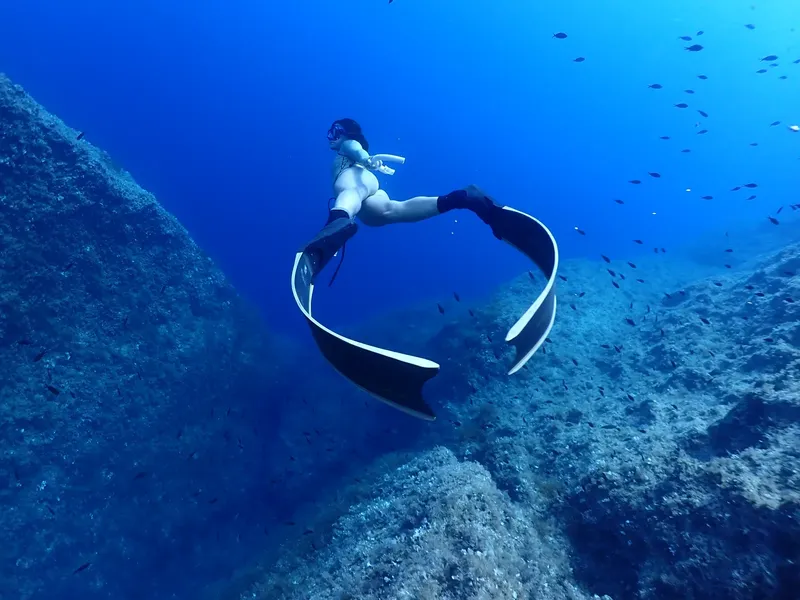 Apnée : une plongeuse évolue entre les rochers et les petits poissons
