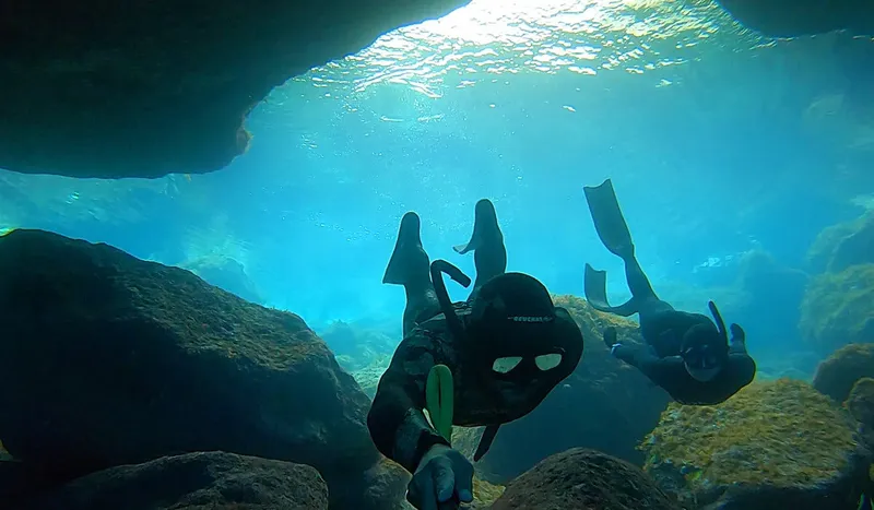 Deux plongeurs explorent une grotte sous-marine avec une lumière vive