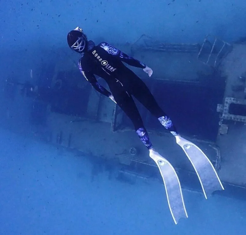 Plongeur en combinaison nageant près d'une structure métallique sous-marine