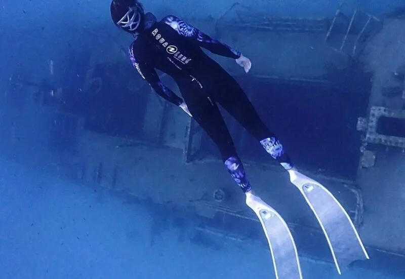 Plongeur en apnée explore une épave sous-marine bleu profond
