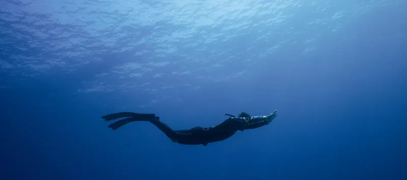 Apnéiste en nage libre dans l'eau bleue, vue sous-marine