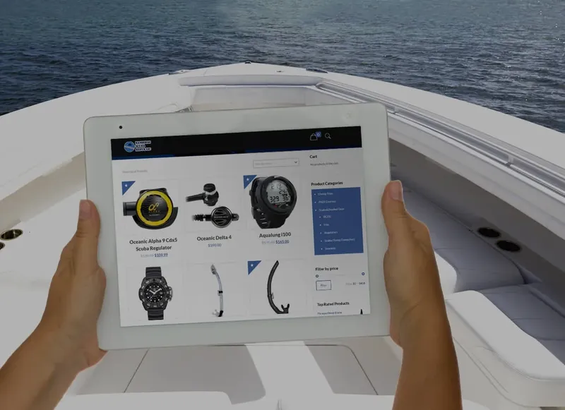 Deux mains tenant une tablette affichant des articles de plongée en mer