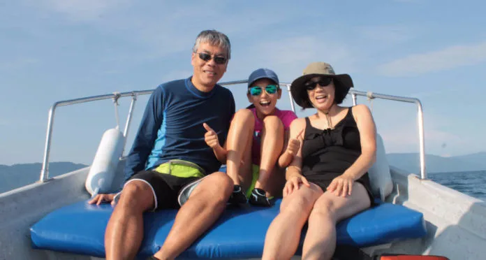 Trois personnes souriantes sur un bateau en mer, journée ensoleillée
