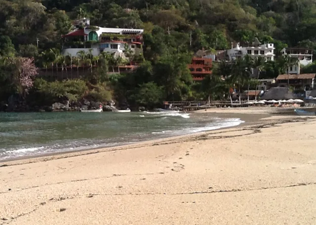 Plage avec bateaux amarrés devant des bâtiments sur une colline