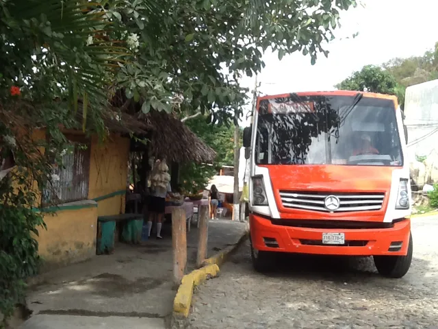 Un bus orange garé devant un bâtiment avec des personnes assises
