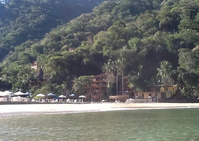 Plage tropicale avec bâtiments sur une colline verdoyante et mer calme