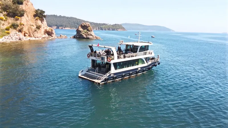 Bateau de plongée en mer avec des passagers, côte rocheuse en arrière-plan