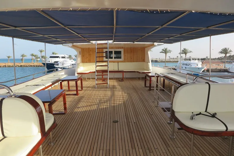 Terrasse en bois d'un bateau de plongée avec sièges et vue sur le port