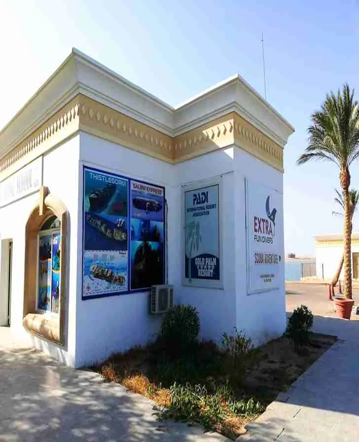 Façade d'un bâtiment blanc avec affiches de sites de plongée