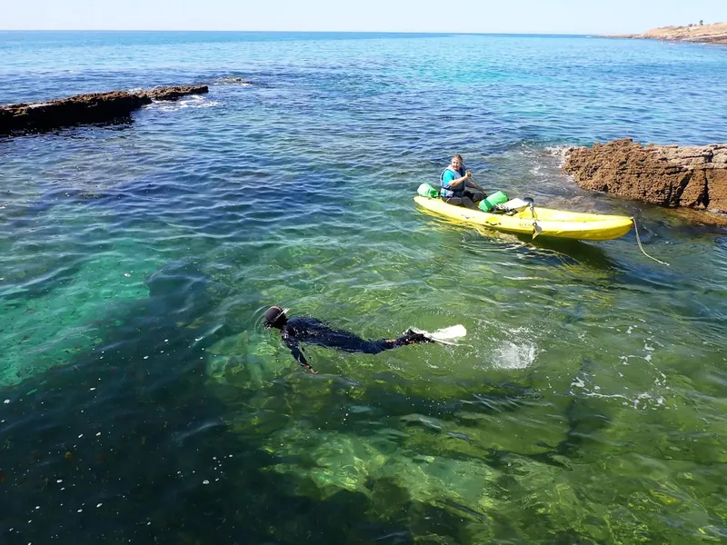Snorkeler nageant près d'un kayak jaune en mer turquoise