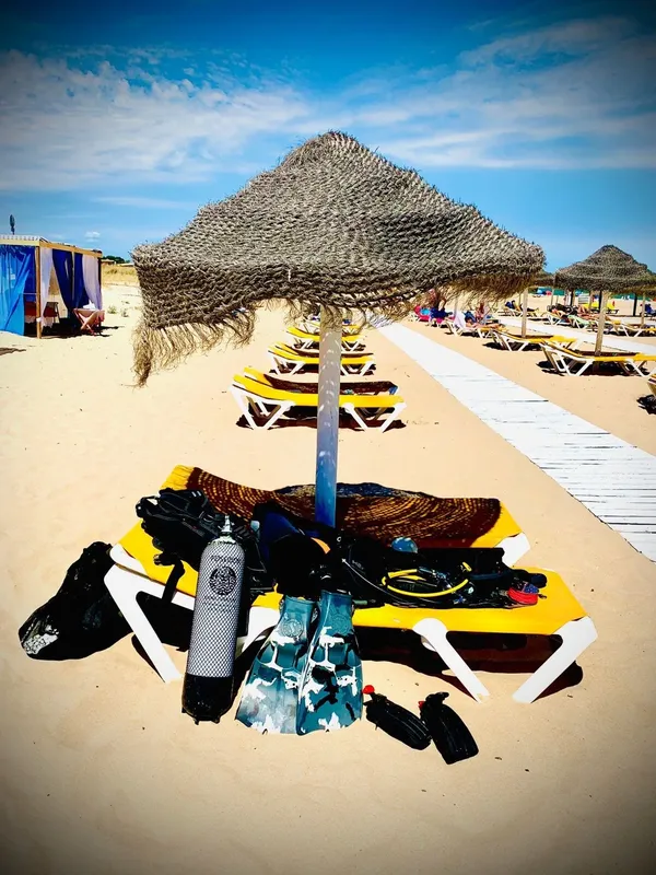 Equipement de plongée sur une plage de sable avec parasols et transats