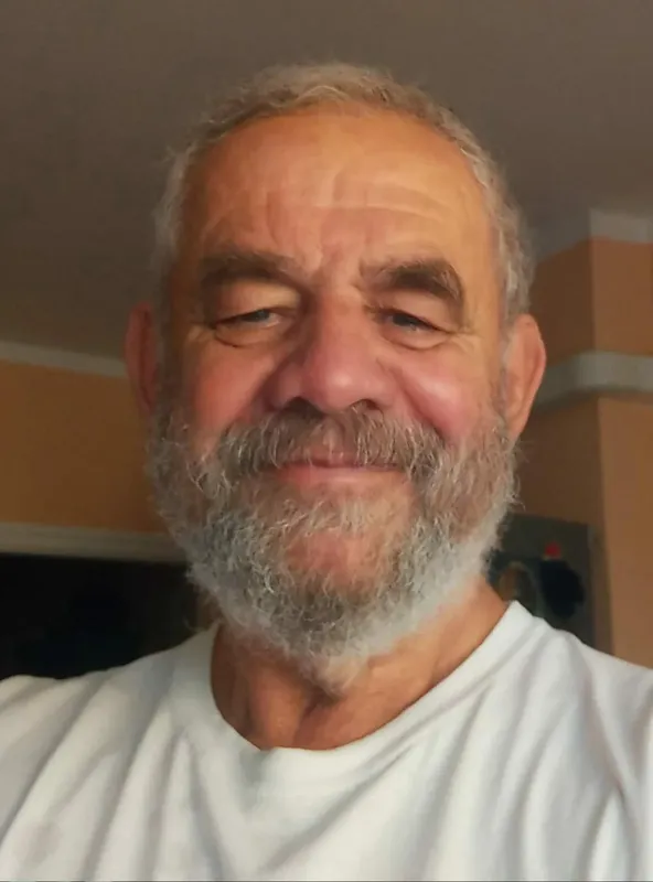 Portrait d'un homme souriant avec une barbe grisonnante et des cheveux courts