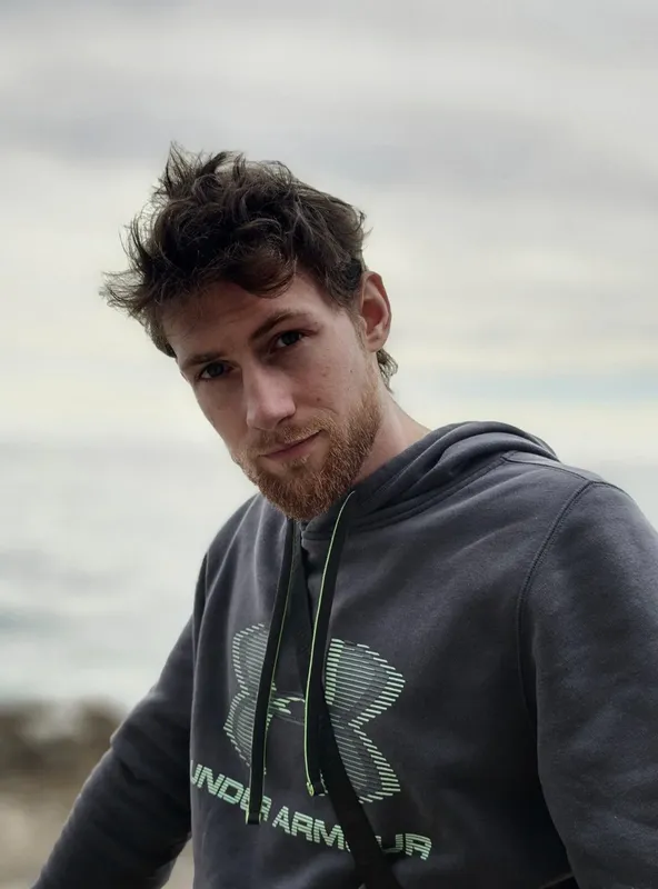 Portrait d'un jeune homme regardant la caméra avec la mer en arrière-plan