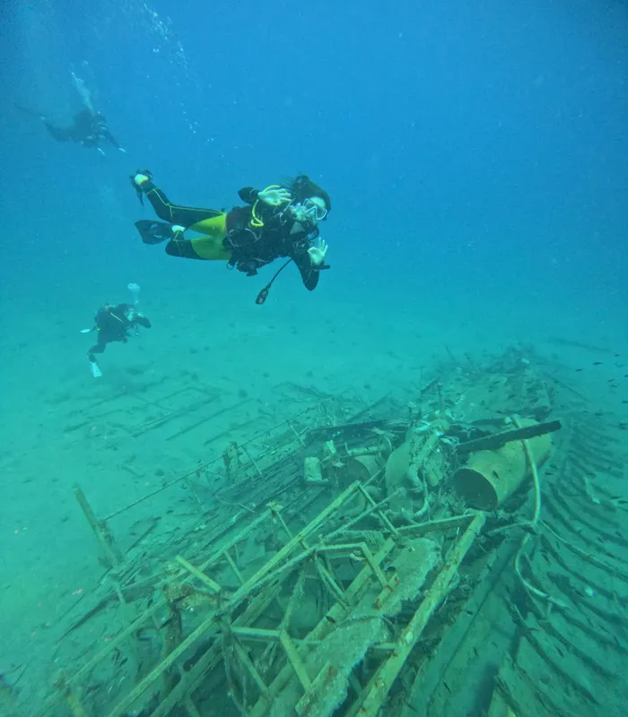 Trois plongeurs explorent une épave métallique au fond de la mer