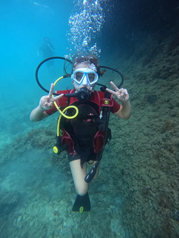 Plongeuse souriante faisant un signe de la main sous l'eau