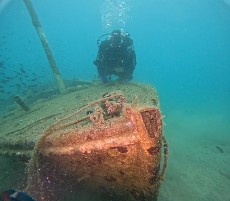 Plongeur explorant l'épave d'un bateau rouillé au fond marin