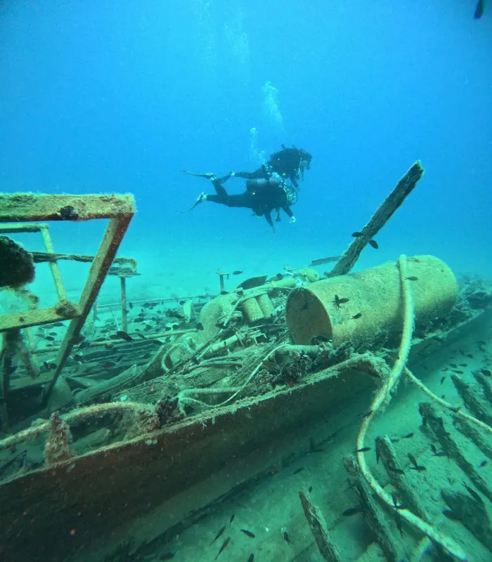 Plongeur explore une épave sous-marine avec des débris métalliques