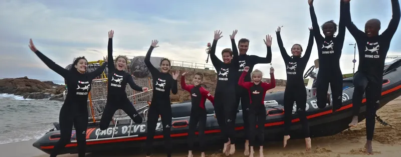 Groupe de plongeurs joyeux sautant devant un bateau pneumatique noir