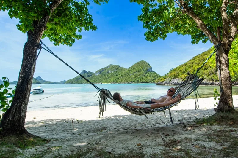 Deux personnes se reposent dans un hamac sur une plage paradisiaque