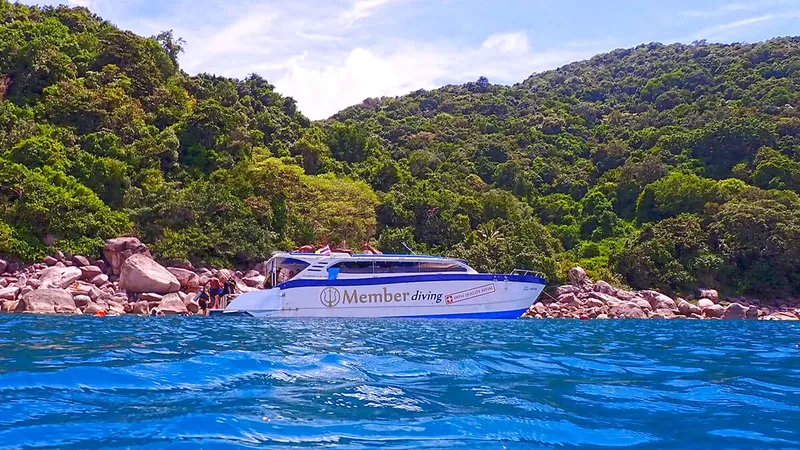 Bateau de plongée amarré devant une plage et une végétation luxuriante