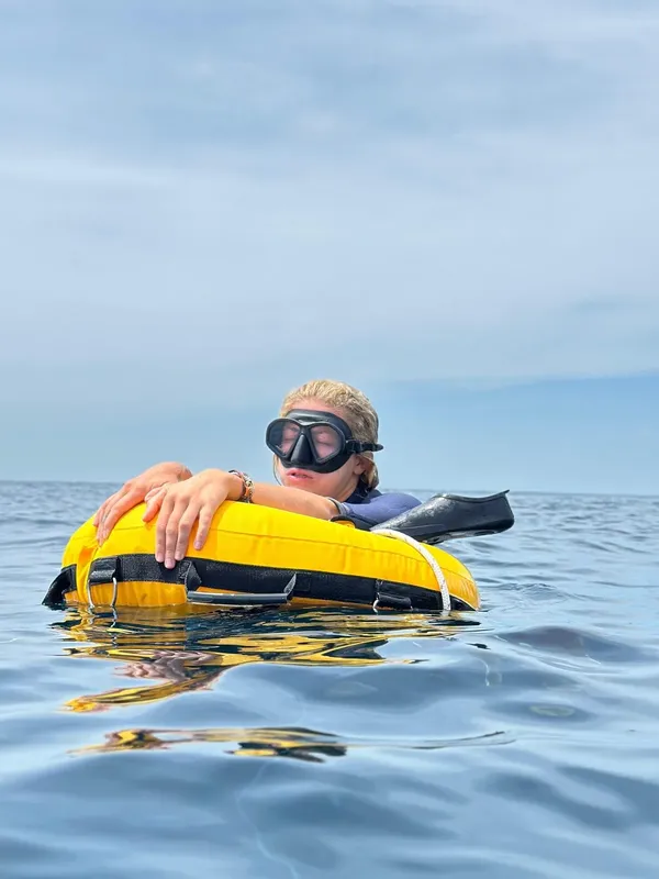 Plongeuse flottant à la surface avec un bouée jaune et masque