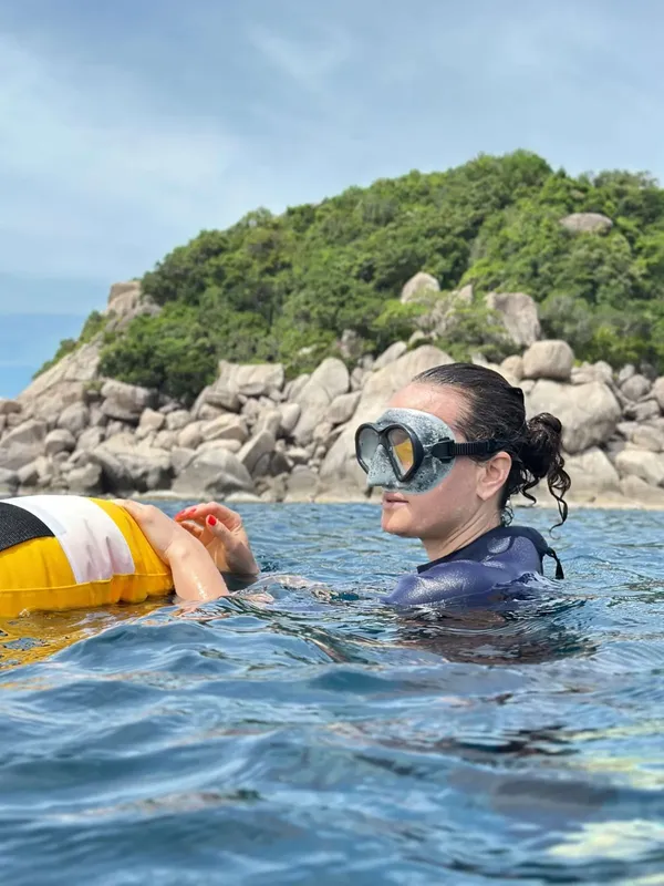 Deux personnes flottent dans l'eau, masque de plongée, île rocheuse