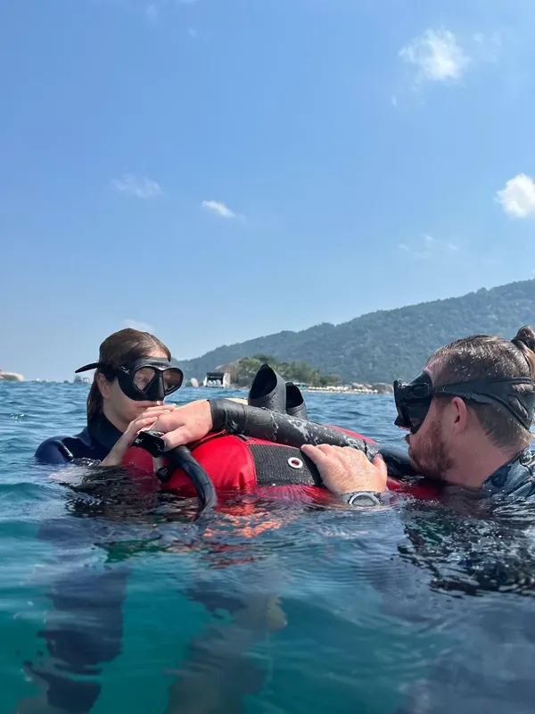 Deux plongeurs en surface, équipés, se regardent dans l'eau turquoise