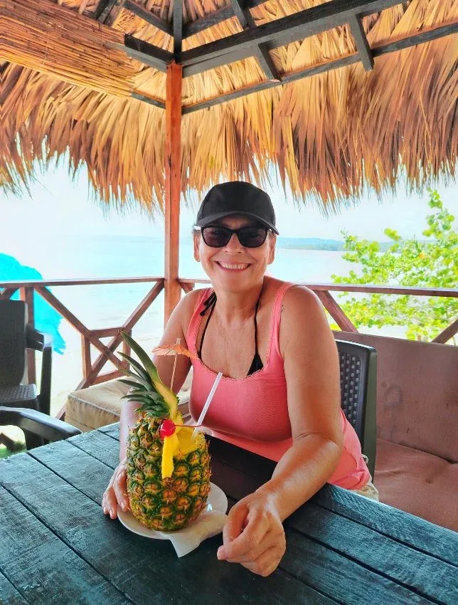 Femme souriante avec un cocktail ananas sur une terrasse ensoleillée