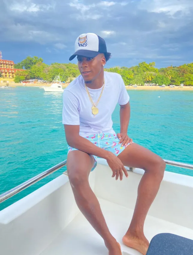 Jeune homme souriant assis sur la proue d'un bateau en mer