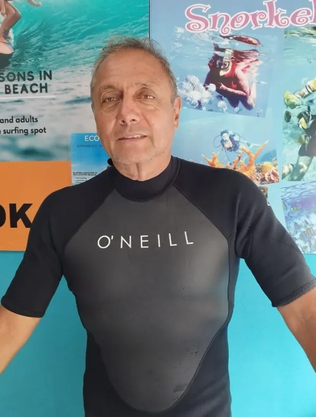 Homme souriant portant une combinaison de plongée devant des affiches