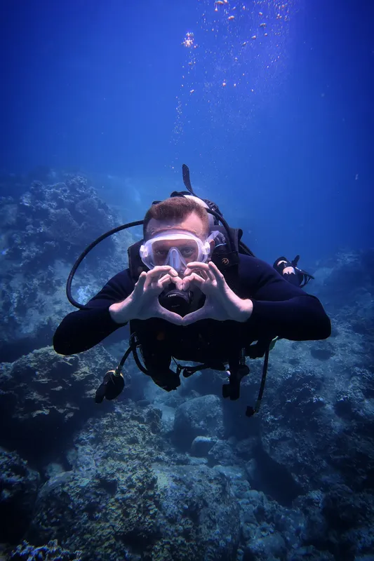 Plongeur souriant formant un cœur avec ses mains sous l'eau
