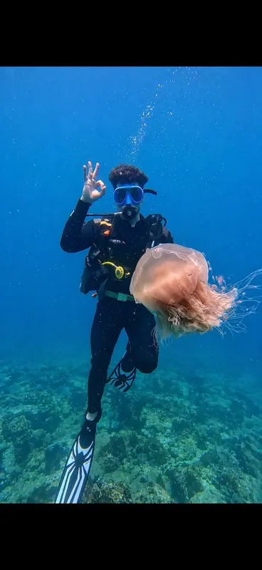 Plongeur souriant avec une méduse géante dans l'eau bleue