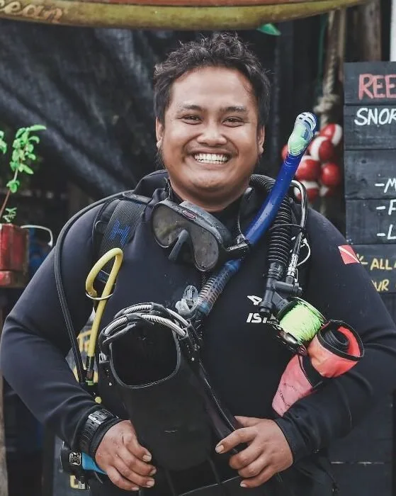 Plongeur souriant équipé de son matériel devant un décor flou
