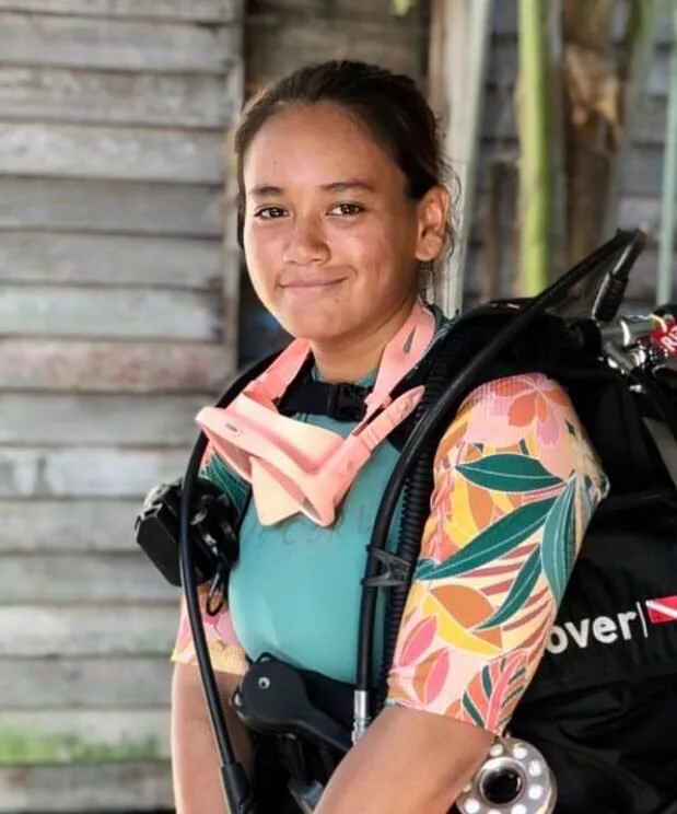 Jeune femme plongeuse souriante avec son équipement complet sur le dos