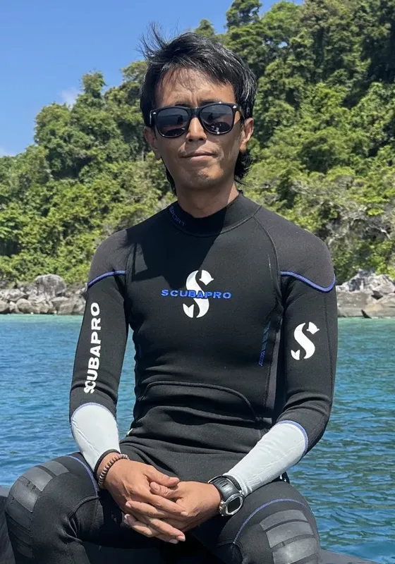 Plongeur en combinaison, lunettes de soleil, assis sur un bateau