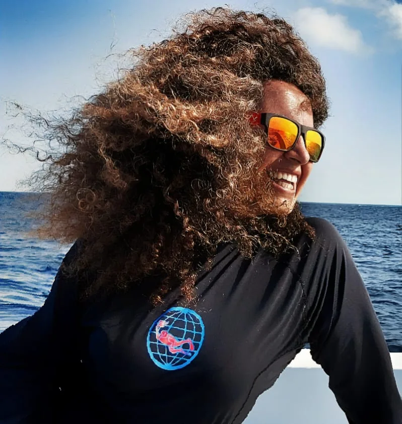 Femme souriante aux cheveux au vent, portant des lunettes de soleil