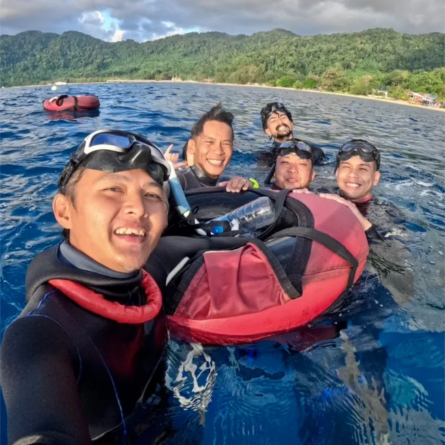 Groupe de plongeurs souriants en mer, avec gilets de sauvetage