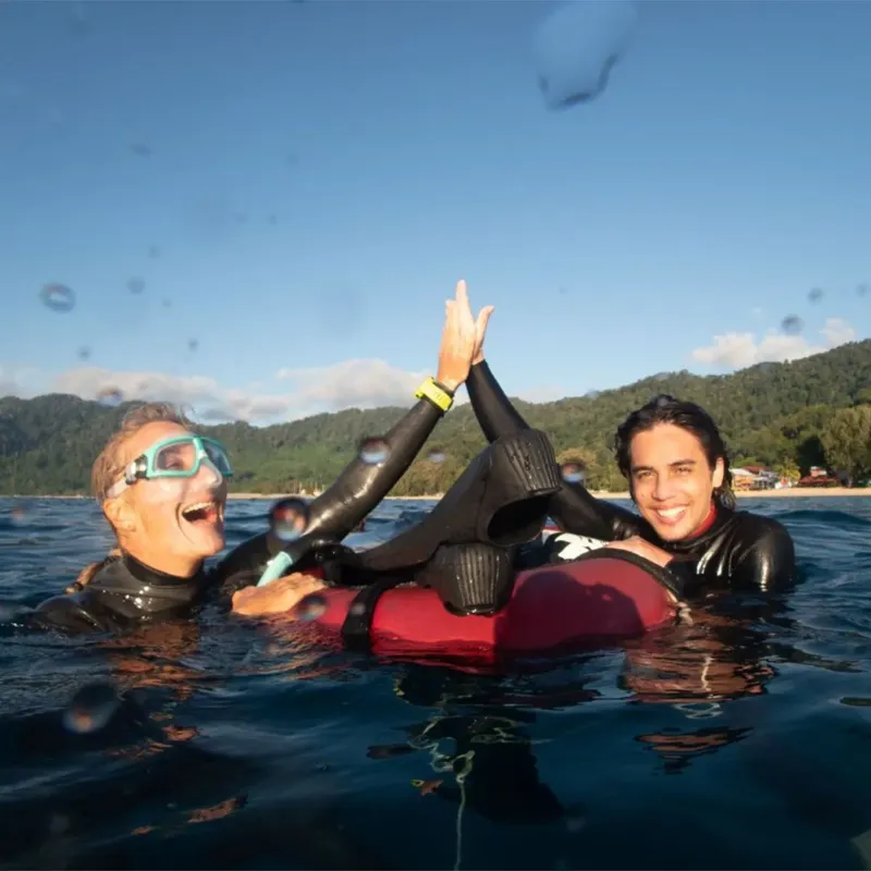 Deux plongeurs souriants se donnent un high-five dans l'eau