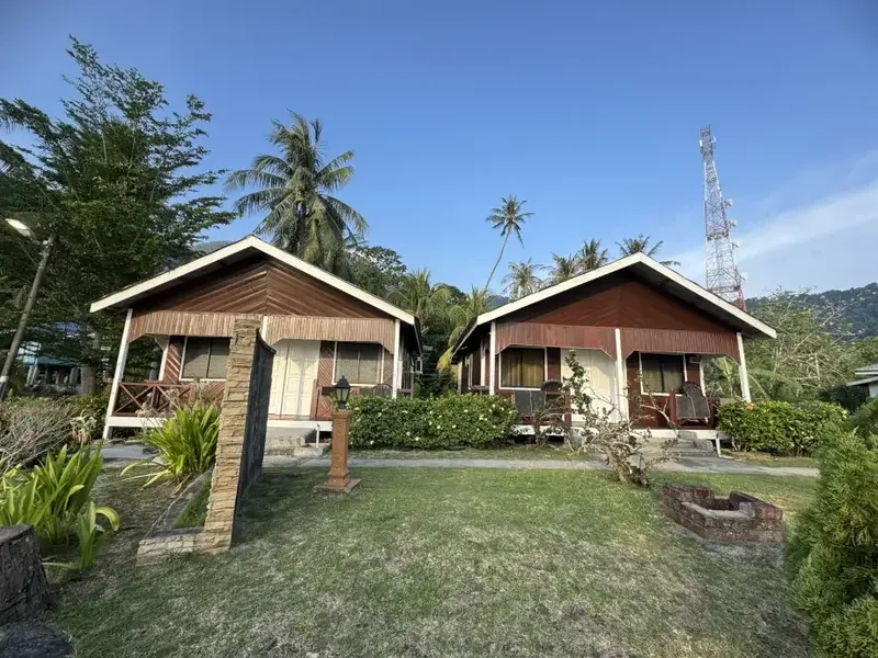 Deux bungalows en bois avec terrasse, pelouse et végétation tropicale