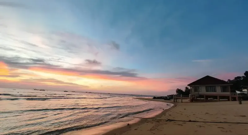 Plage de sable fin avec un bâtiment et un ciel coloré