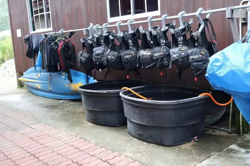 Rangée de gilets de plongée noirs suspendus près de bacs de rinçage