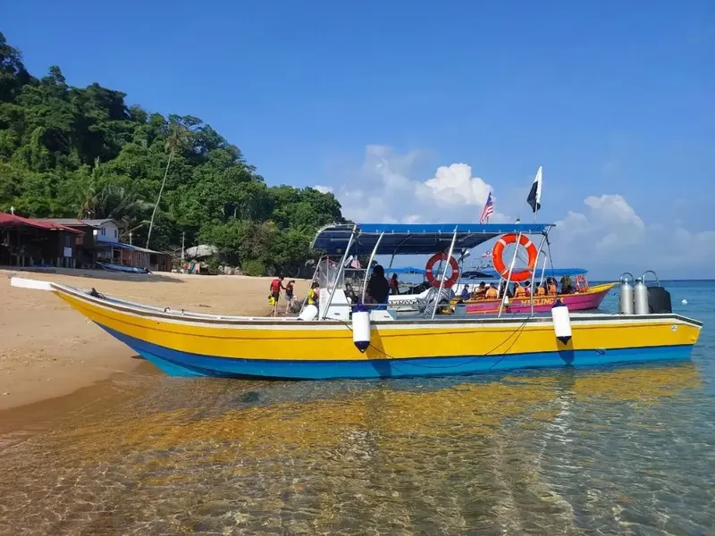 Bateau de plongée jaune et bleu amarré sur une plage tropicale