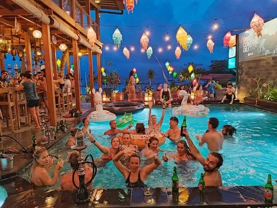 Ambiance festive au bord d'une piscine illuminée avec des convives souriants