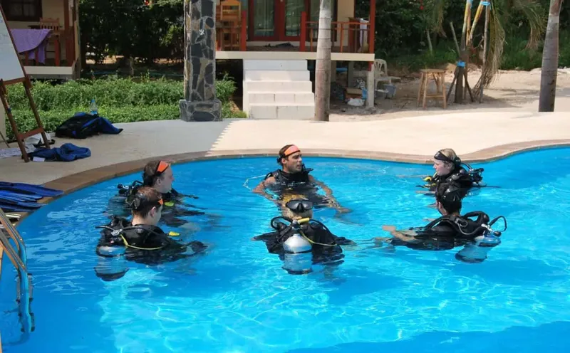 Quatre plongeurs en formation dans une piscine avec leur équipement