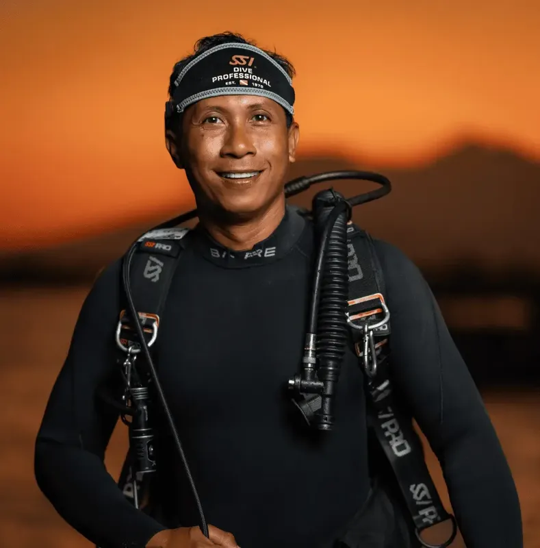 Plongeur souriant portant son équipement complet et un bonnet