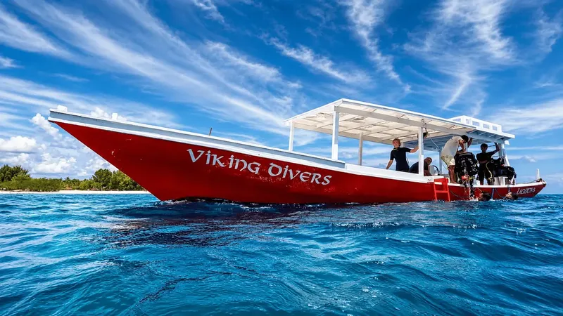 Bateau de plongée rouge avec des plongeurs à bord en mer